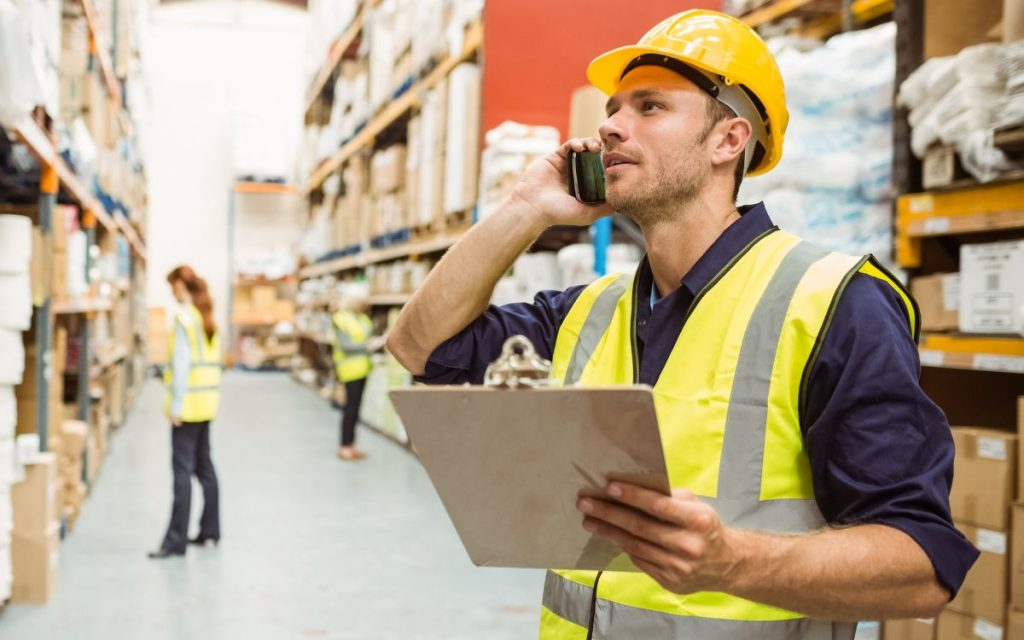 The warehouse manager is talking on the mobile phone.